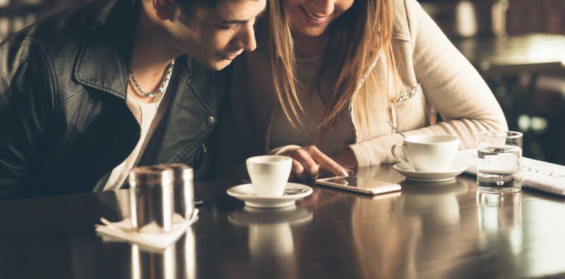 A couple laughing while discussing their favorite hobbies during their first date over coffee.